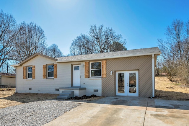 view of front of house with brick siding, concrete driveway, roof with shingles, french doors, and crawl space