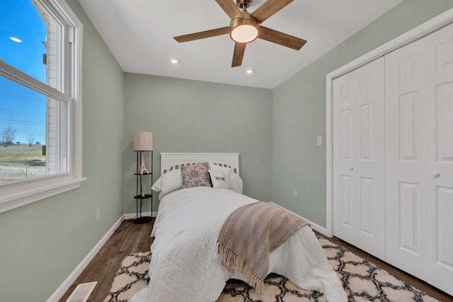 bedroom featuring visible vents, baseboards, wood finished floors, a closet, and a ceiling fan