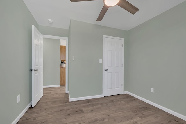 unfurnished bedroom with a ceiling fan, wood finished floors, and baseboards