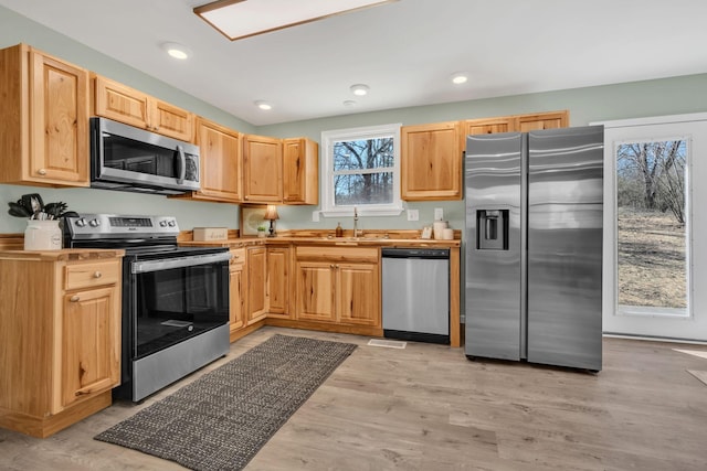 kitchen with light brown cabinets, recessed lighting, a sink, stainless steel appliances, and light wood-type flooring