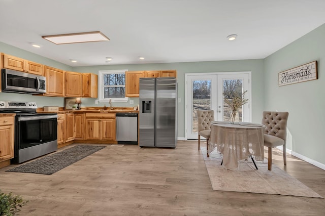 kitchen with light wood finished floors, plenty of natural light, appliances with stainless steel finishes, and a sink