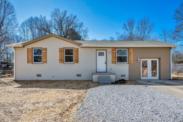 ranch-style house featuring driveway, a shingled roof, french doors, crawl space, and brick siding