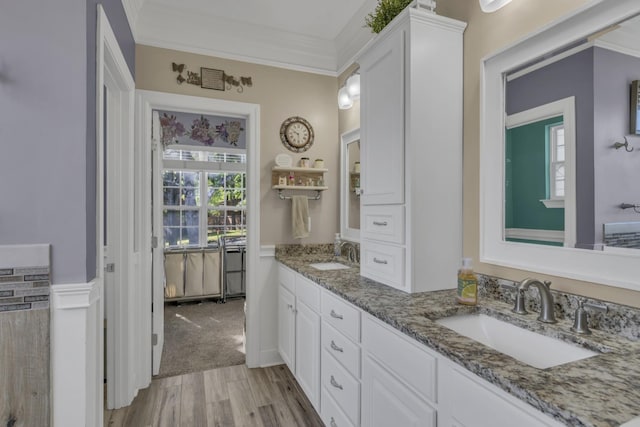 bathroom with double vanity, ornamental molding, wood finished floors, and a sink