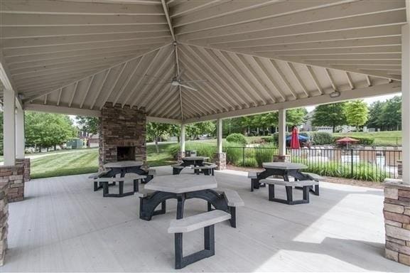 view of patio / terrace featuring outdoor dining space, a gazebo, fence, and an outdoor stone fireplace