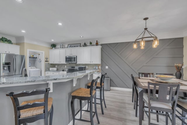 kitchen with white cabinetry, crown molding, a breakfast bar area, and stainless steel appliances