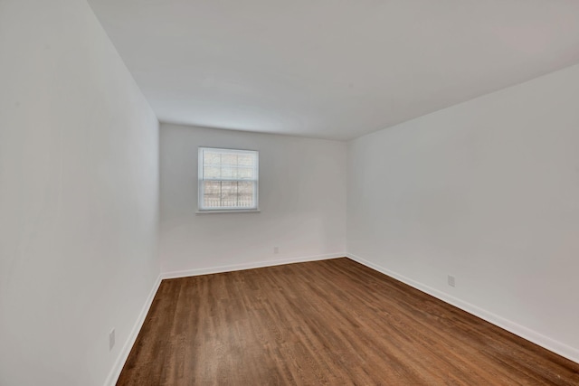 empty room featuring dark wood-type flooring and baseboards