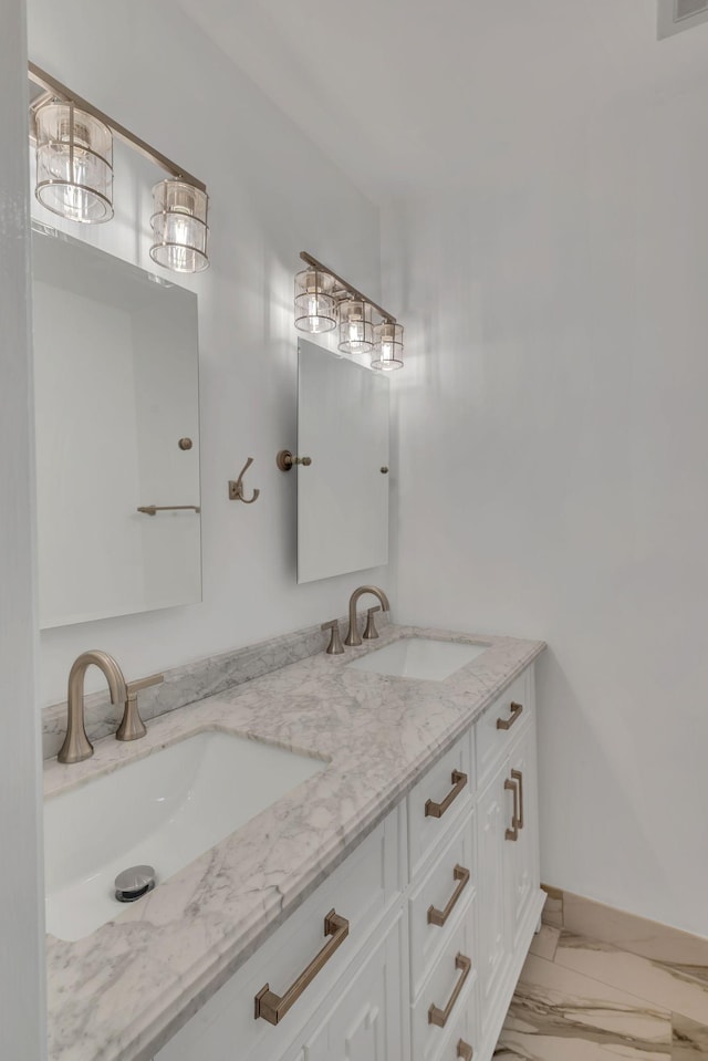 full bath with double vanity, baseboards, marble finish floor, and a sink