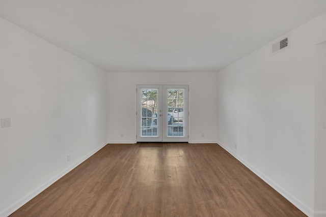 spare room with wood finished floors, french doors, visible vents, and baseboards