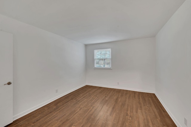 spare room featuring dark wood-style floors and baseboards