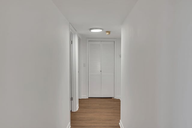 corridor with dark wood finished floors and baseboards