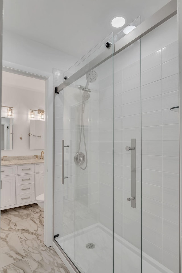 bathroom featuring a shower stall, double vanity, marble finish floor, and a sink