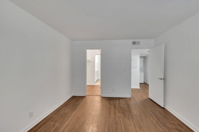 spare room featuring visible vents, baseboards, and dark wood-style floors