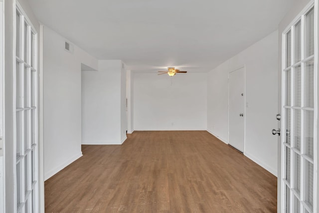 unfurnished room featuring baseboards, wood finished floors, visible vents, and ceiling fan