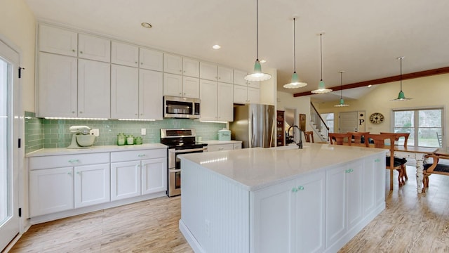 kitchen with light wood finished floors, backsplash, appliances with stainless steel finishes, and a sink