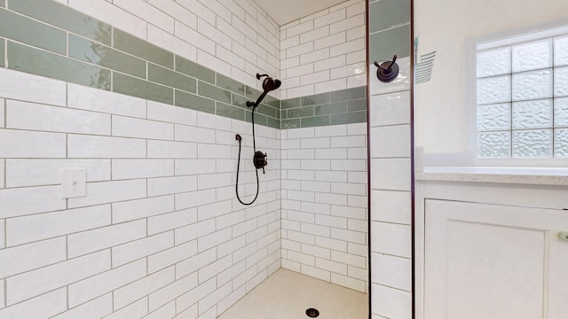 bathroom with plenty of natural light, tiled shower, and vanity