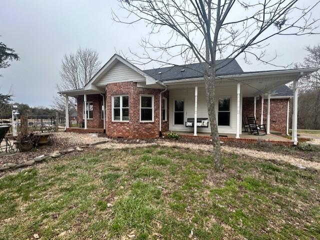 rear view of house featuring a lawn and brick siding