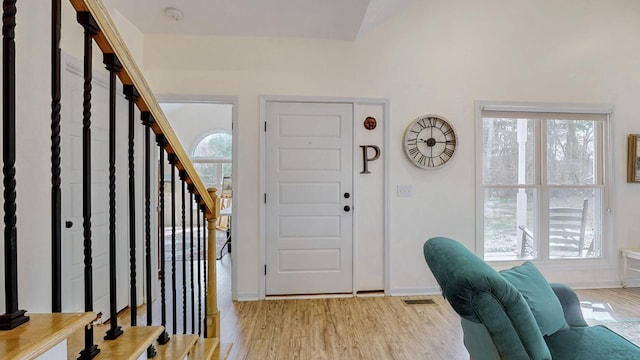 foyer entrance with a wealth of natural light, baseboards, light wood-style flooring, and stairs