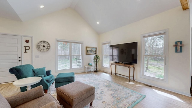 living area with a wealth of natural light, high vaulted ceiling, baseboards, and wood finished floors