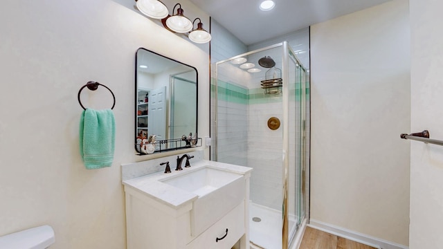 bathroom with vanity, a shower stall, wood finished floors, and baseboards