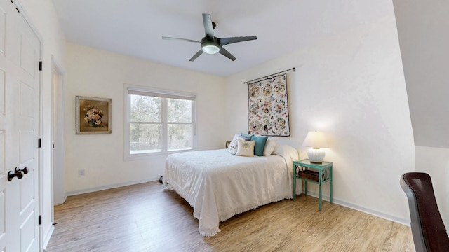 bedroom with baseboards, light wood-style flooring, and a ceiling fan