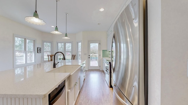 kitchen featuring plenty of natural light, appliances with stainless steel finishes, light wood-style flooring, and hanging light fixtures