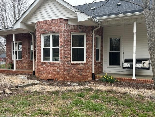 exterior space with brick siding, covered porch, and a shingled roof