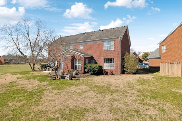 rear view of property featuring fence, a lawn, and brick siding