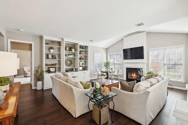 living area with lofted ceiling, dark wood-style floors, visible vents, and a wealth of natural light