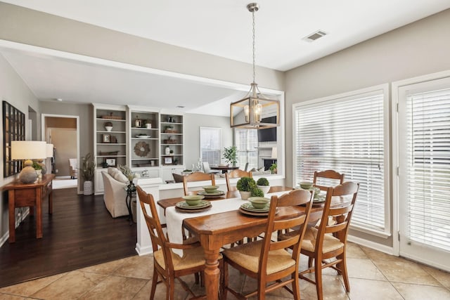 dining room with light tile patterned floors, visible vents, and a chandelier