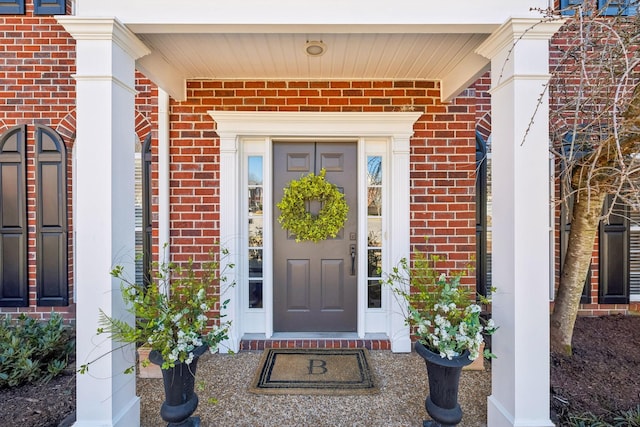 doorway to property with a porch and brick siding