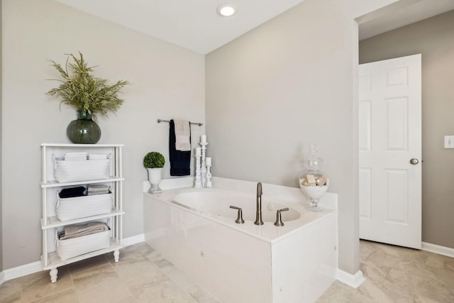 bathroom featuring baseboards and a bath