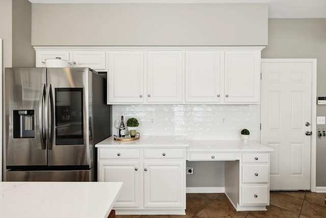 kitchen with dark tile patterned floors, stainless steel fridge, tasteful backsplash, and light countertops