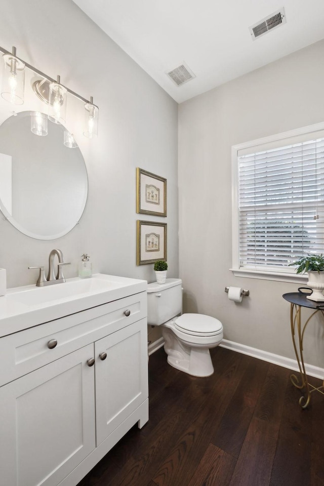 bathroom featuring visible vents, baseboards, toilet, and wood finished floors