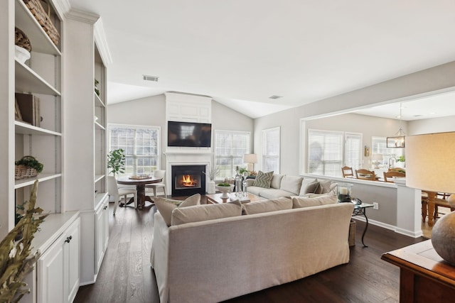 living room with visible vents, lofted ceiling, plenty of natural light, and dark wood finished floors