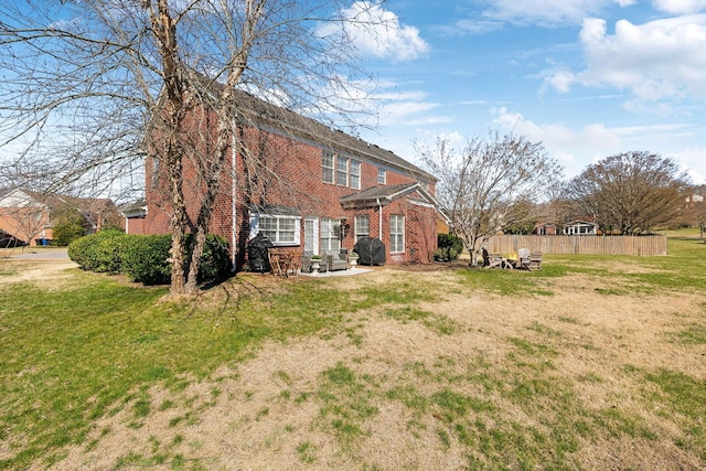 rear view of property with a patio, fence, brick siding, and a lawn