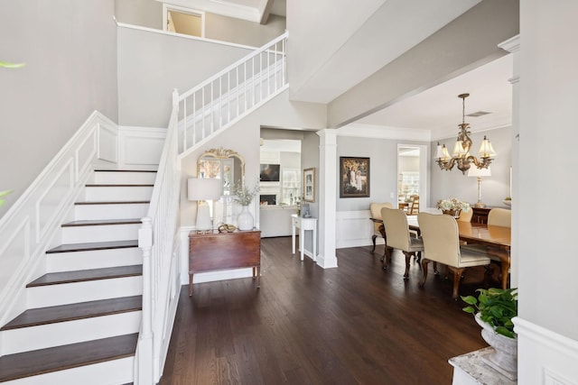 interior space with wood finished floors, stairway, wainscoting, a decorative wall, and decorative columns