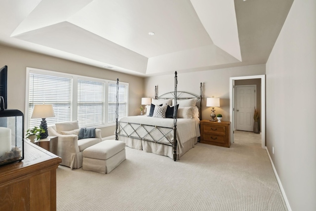 bedroom with light carpet, baseboards, and a tray ceiling