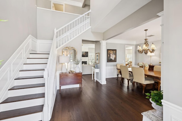 entryway with crown molding, a wainscoted wall, stairs, decorative columns, and wood finished floors