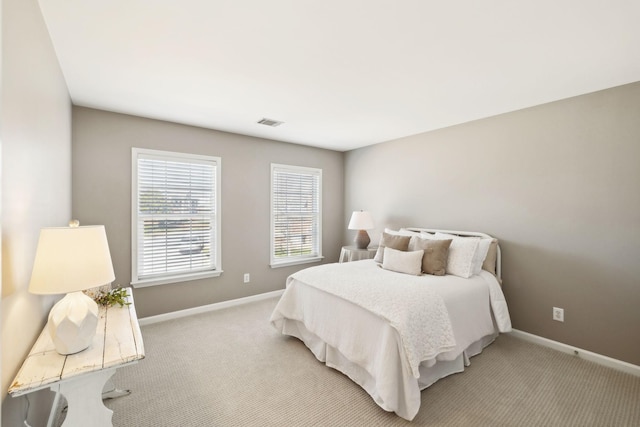 bedroom featuring visible vents, light colored carpet, and baseboards