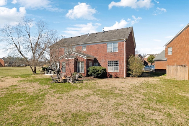 back of property featuring a yard, fence, and brick siding