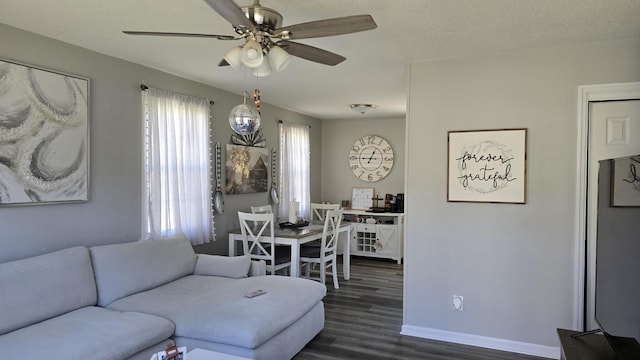 living area with dark wood-style floors, a textured ceiling, baseboards, and ceiling fan