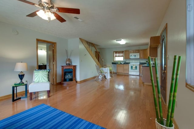 living area featuring visible vents, stairway, light wood-style floors, a fireplace, and baseboards