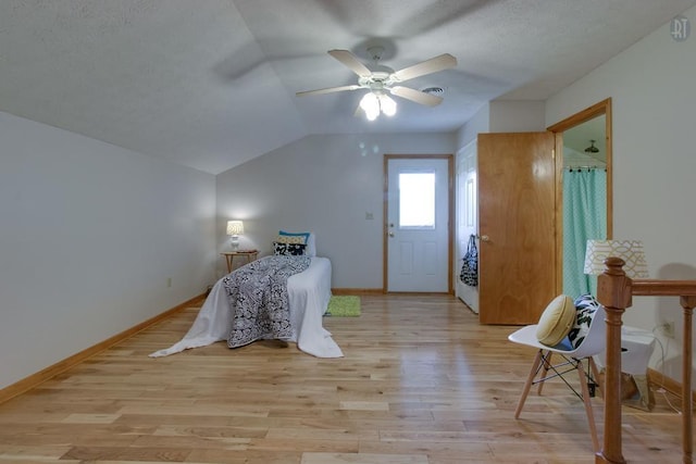 bedroom with light wood finished floors, baseboards, and vaulted ceiling