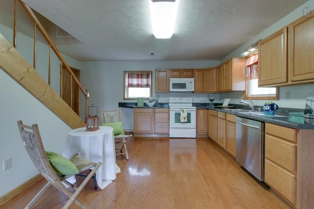 kitchen with white appliances, light wood-style flooring, plenty of natural light, and a sink