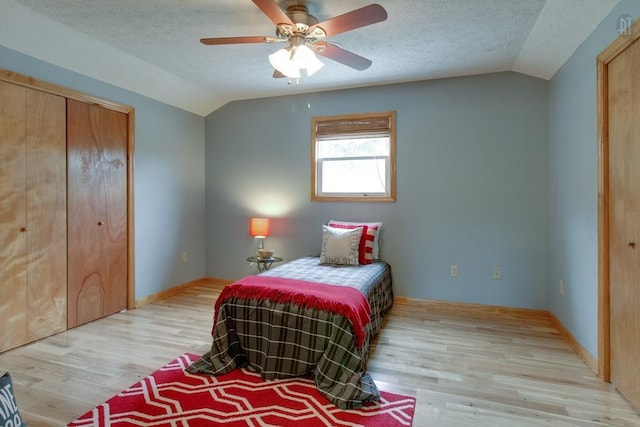 bedroom featuring light wood-style flooring, a textured ceiling, ceiling fan, and vaulted ceiling