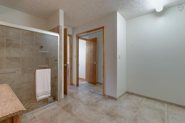 bathroom featuring baseboards, a textured ceiling, and a shower stall