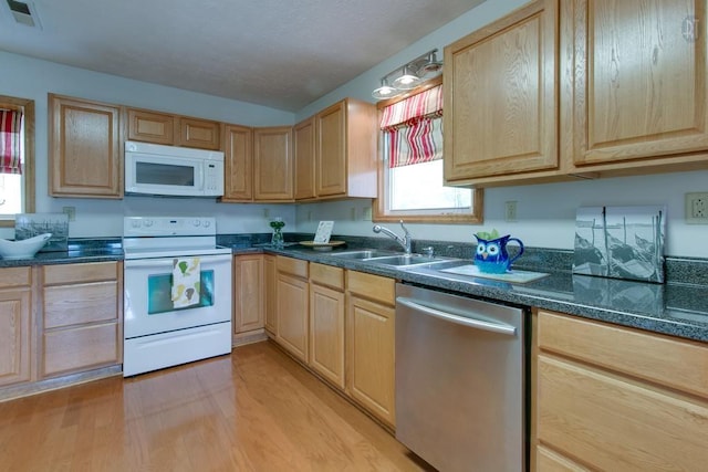 kitchen with white appliances, visible vents, light brown cabinetry, and a sink