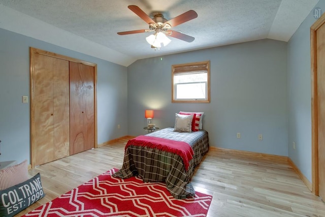 bedroom with a closet, a textured ceiling, wood finished floors, and vaulted ceiling