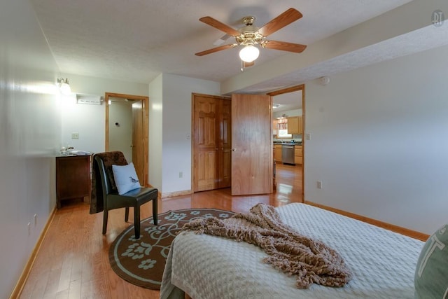 bedroom with ceiling fan, a textured ceiling, light wood-type flooring, and baseboards