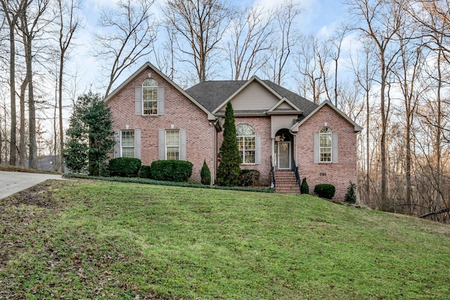 traditional-style house featuring a front yard, brick siding, and roof with shingles